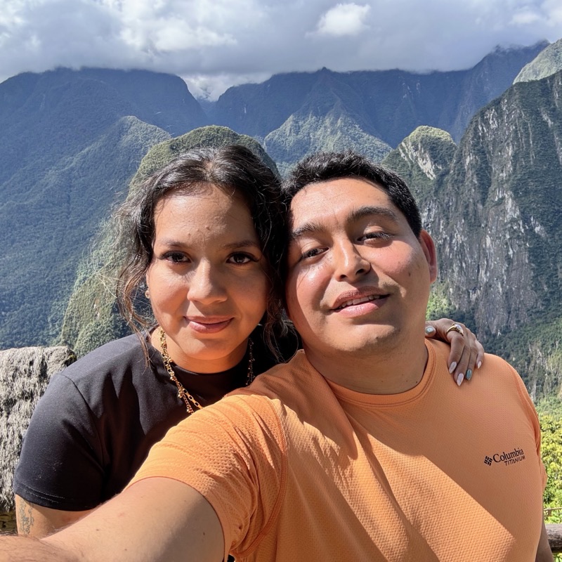Dennis y Paola sonriendo juntos frente a las montañas